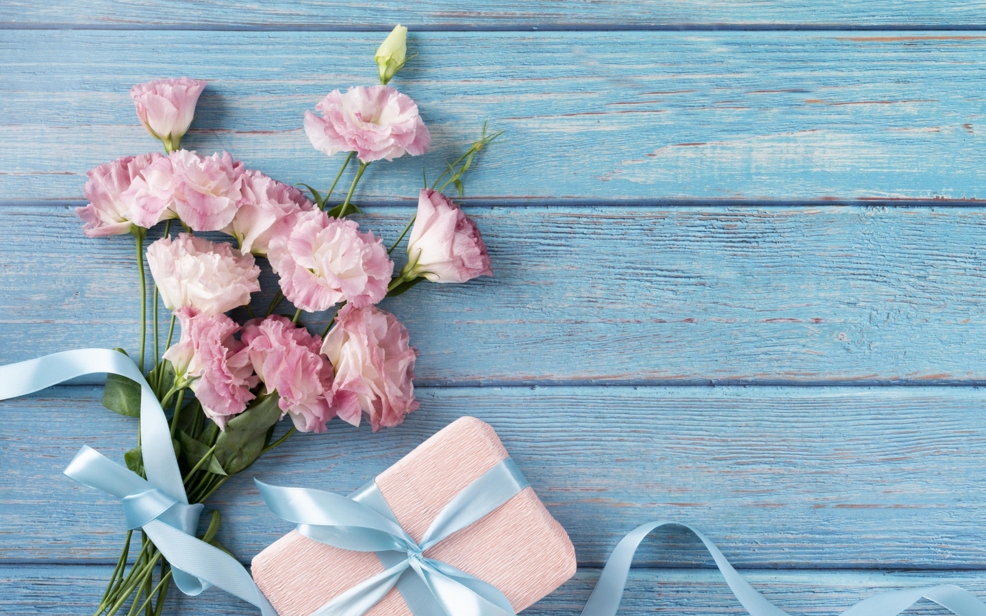 Букет розовой эустомы с подарком на голубом фоне