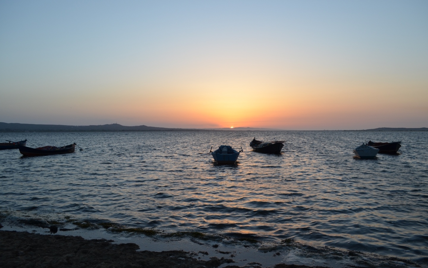 Лодки на морском побережье на закате