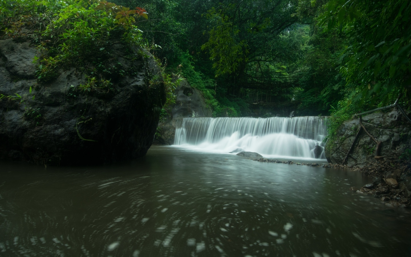 Водопад стекает в реку с большими камнями в лесу