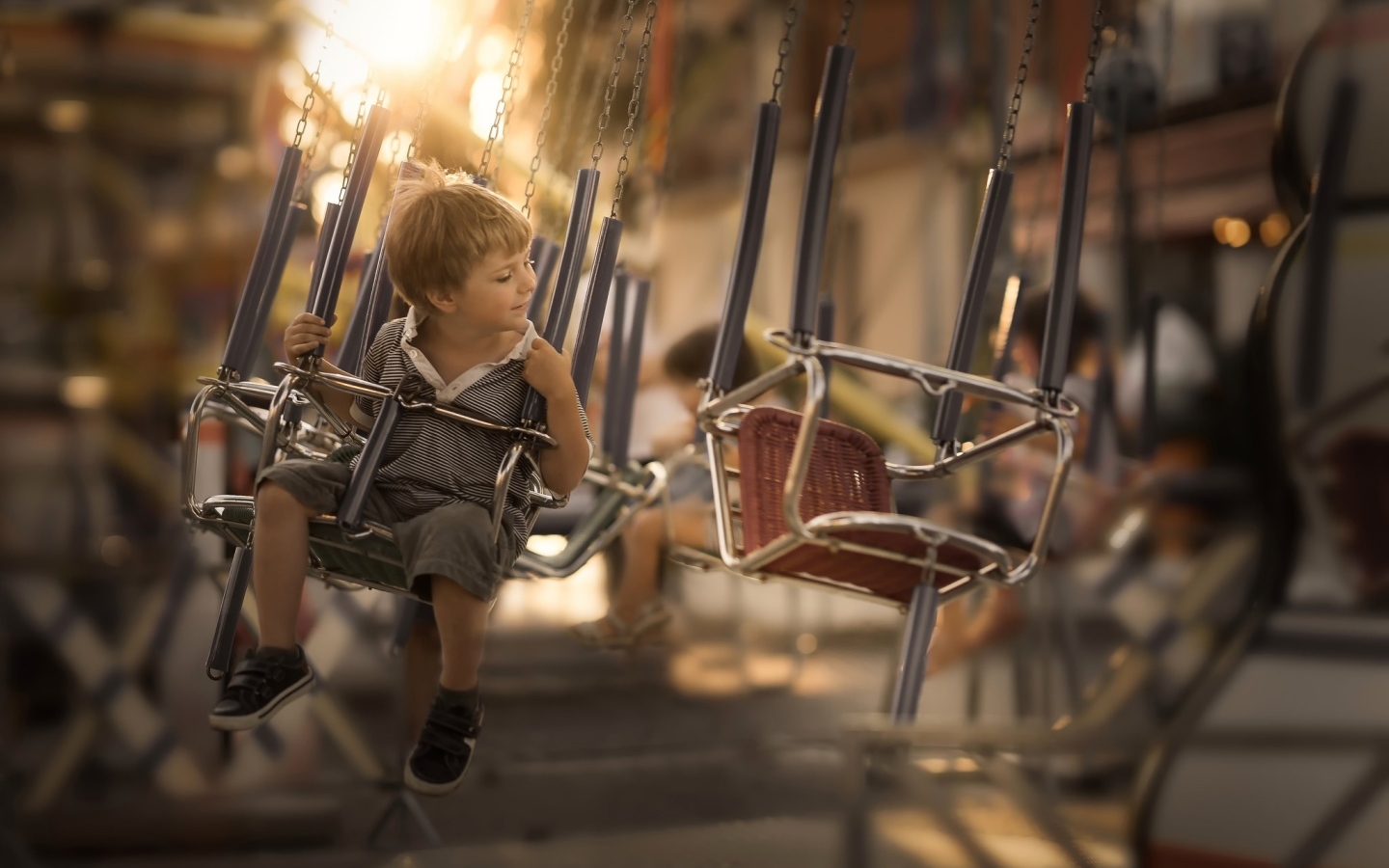 Маленький мальчик катается на каруселях
