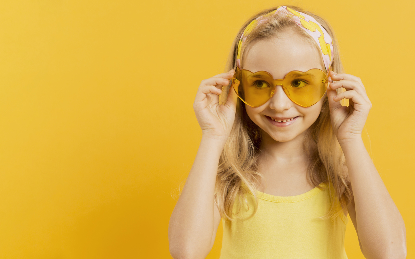 Красивая девочка блондинка в очках в форме сердца на желтом фоне