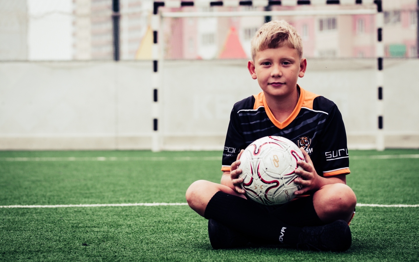 Мальчик футболист сидит на траве с мячом