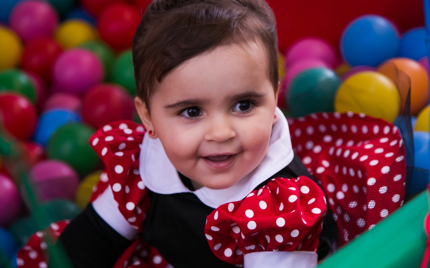 Кареглазая девочка в бассейне с шариками