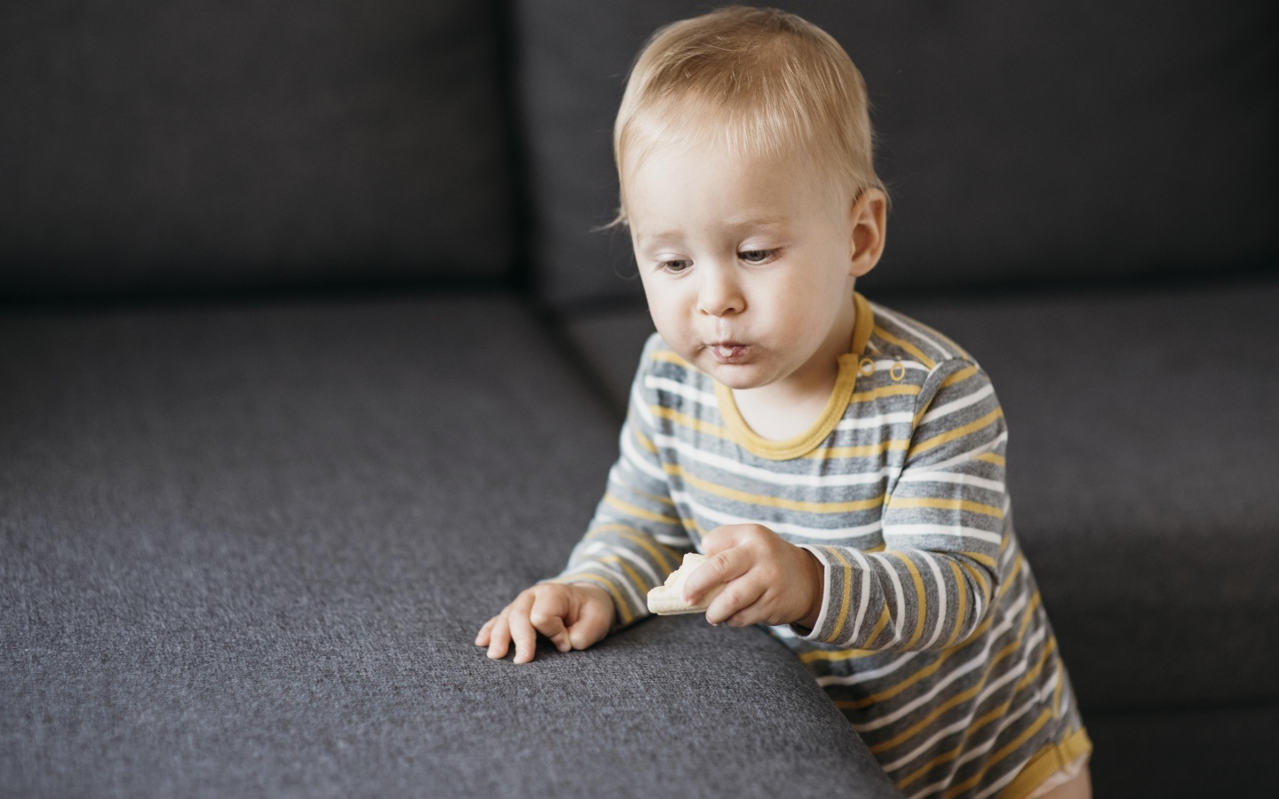 Любопытный маленький ребенок у дивана