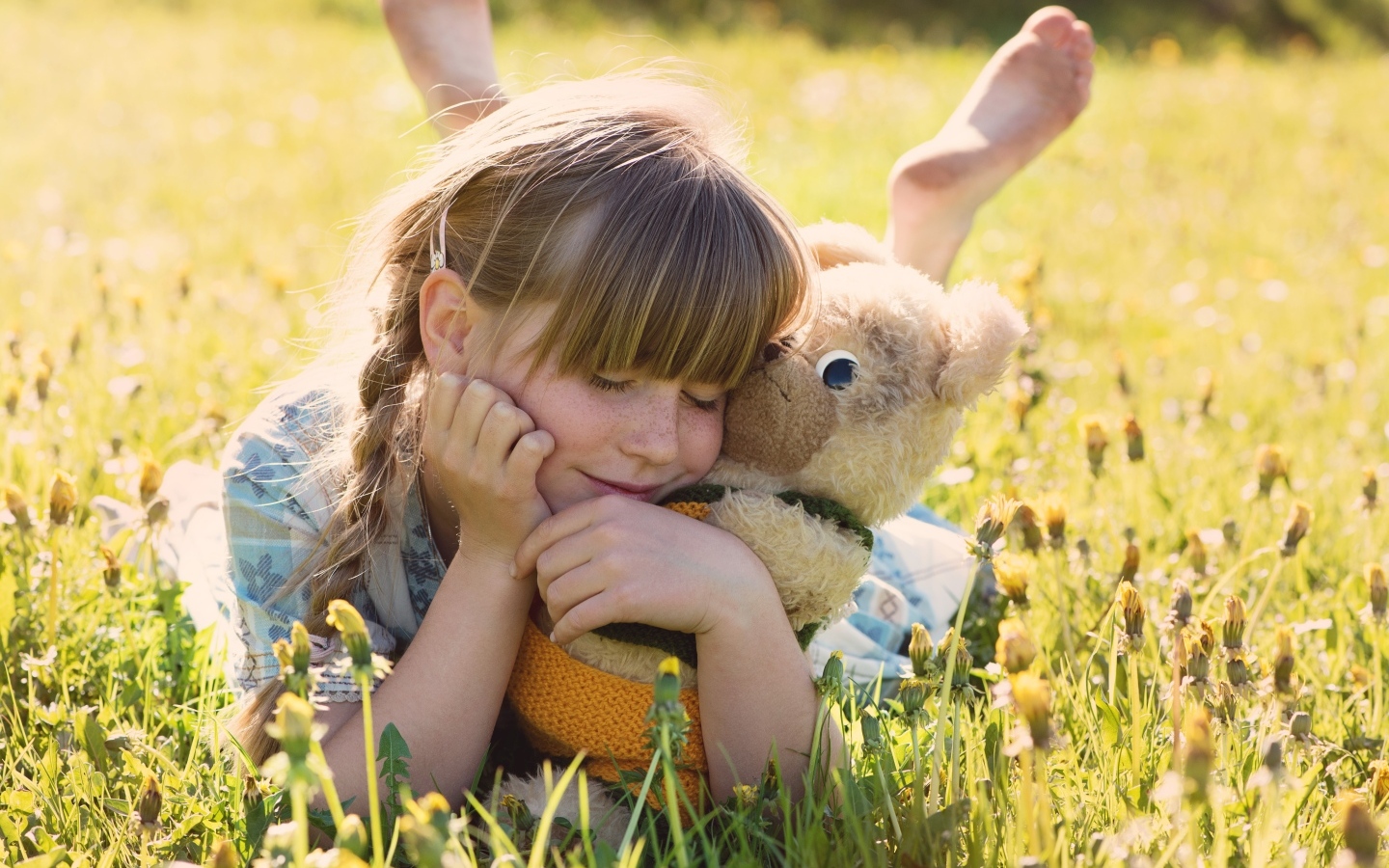 Девочка с игрушкой лежат на траве