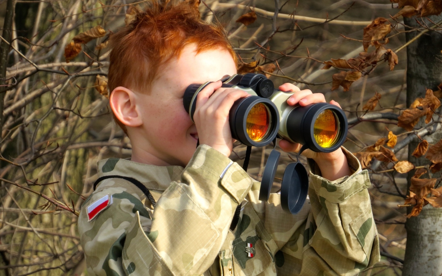 Маленький мальчик в военной форме с биноклем в руках