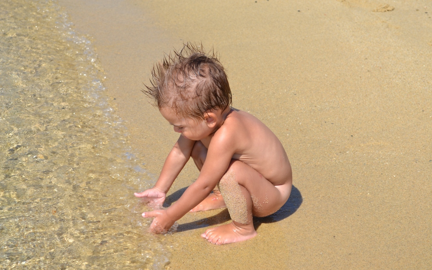 Маленький мальчик на пляже у моря на песке