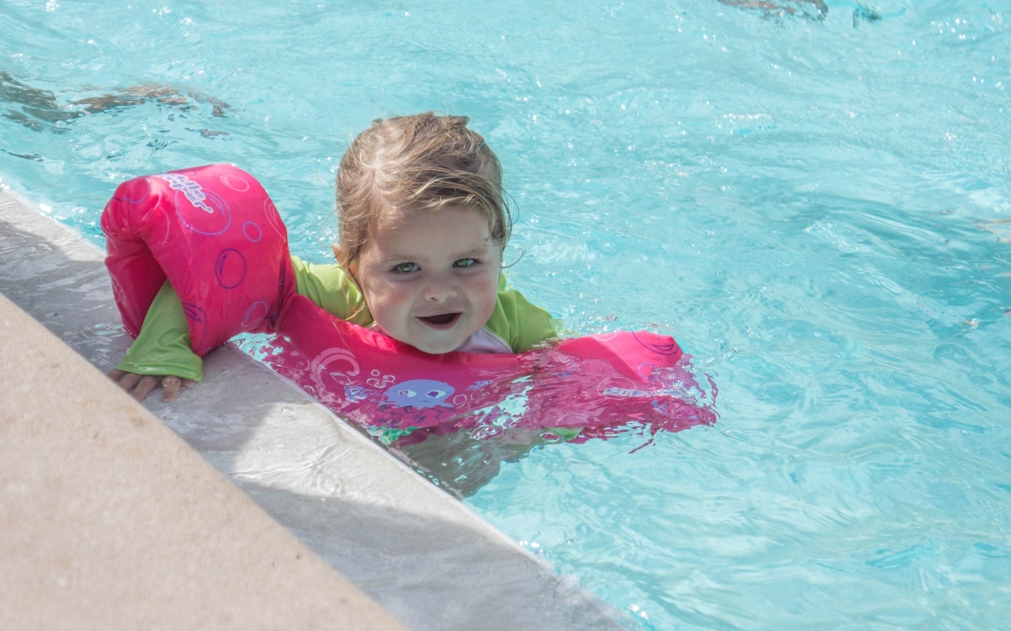 Маленькая девочка со спасательным кругом в бассейне