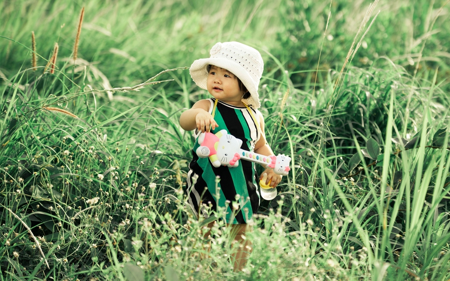 Маленькая девочка с игрушечной гитарой в траве