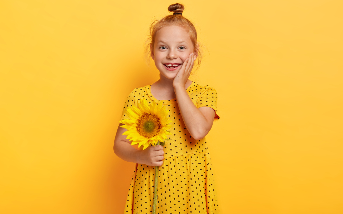 Маленькая рыжеволосая девочка с подсолнухом в руках