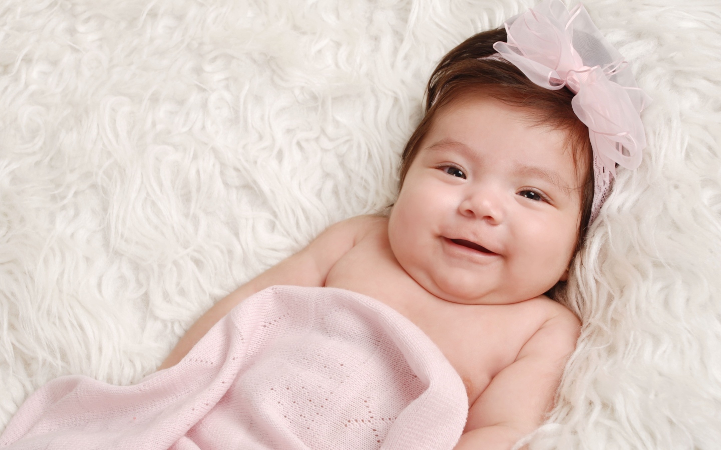 Улыбающаяся новорожденная малышка с бантом на голове