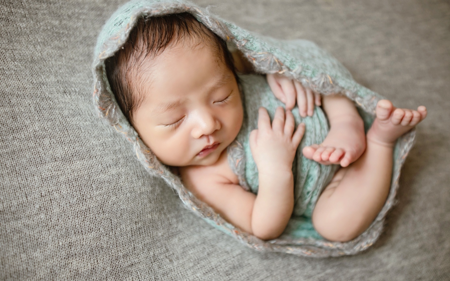 Крошечный новорожденный малыш на сером фоне