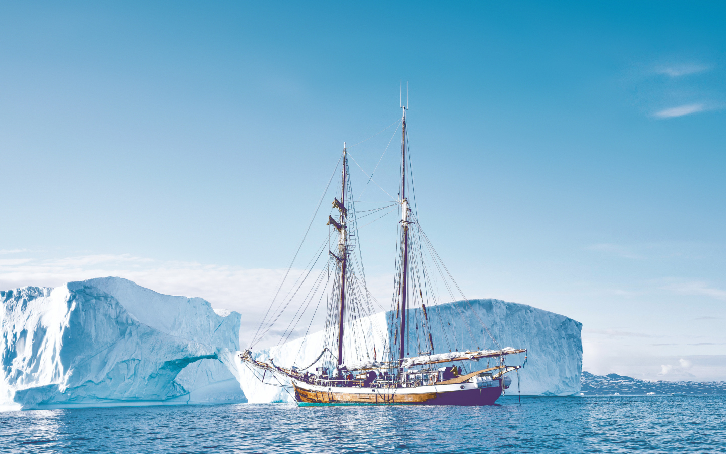 Большой корабль подплывает к голубому айсбергу в море