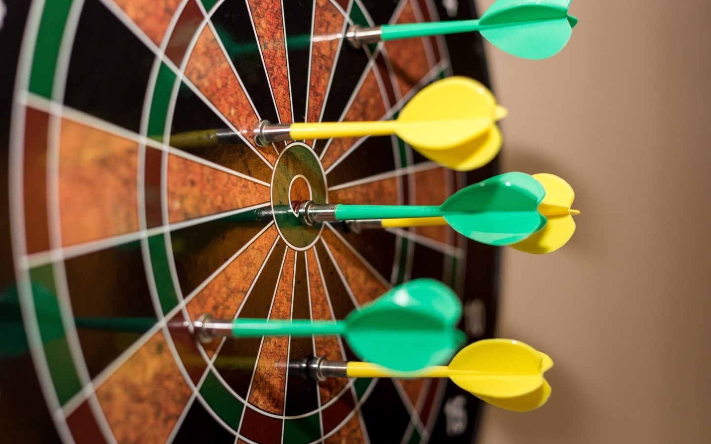 Желтые и зеленые дротики в мишени 