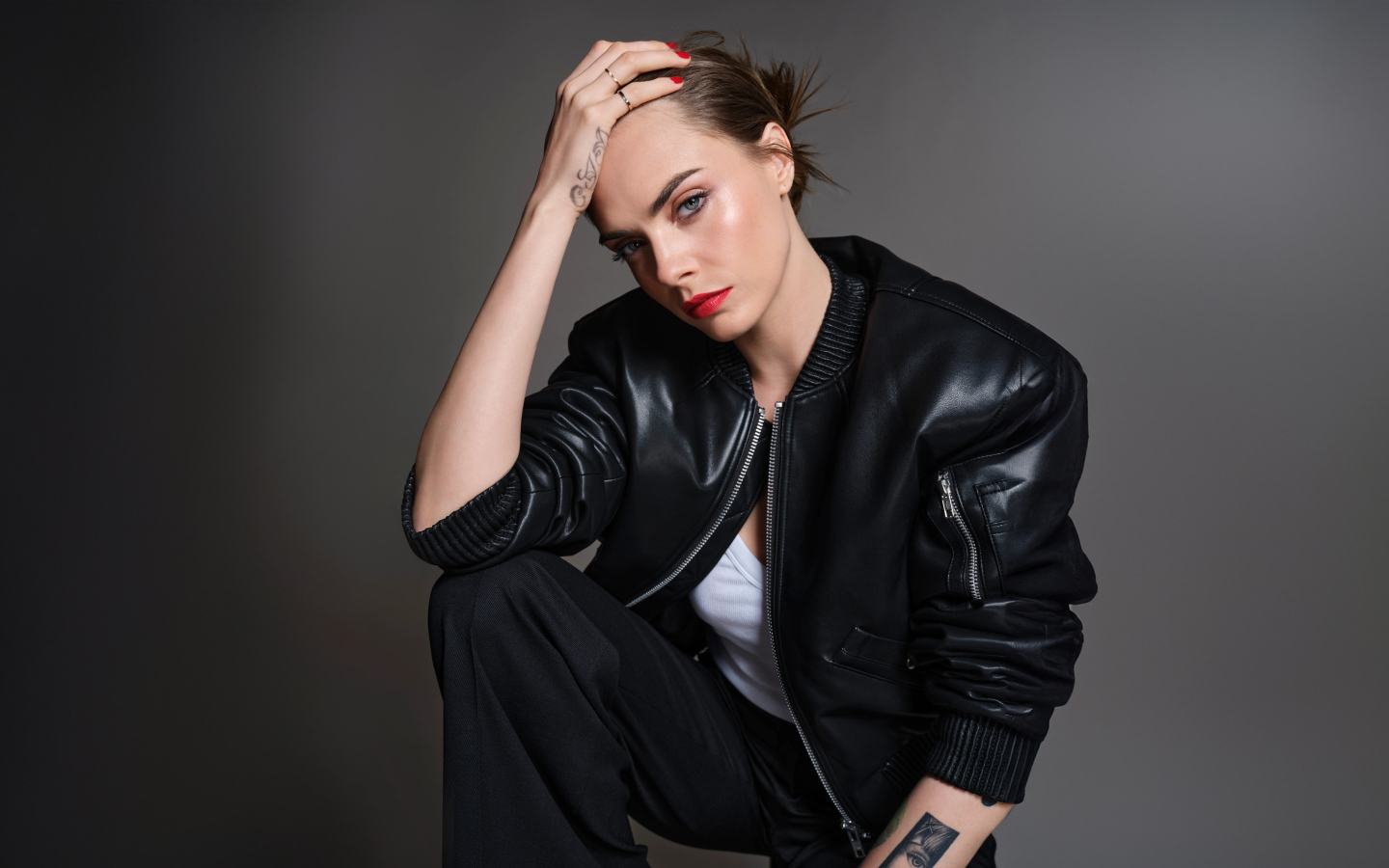 Актриса Кара Делевинь в черной кожаной куртке на сером фоне
