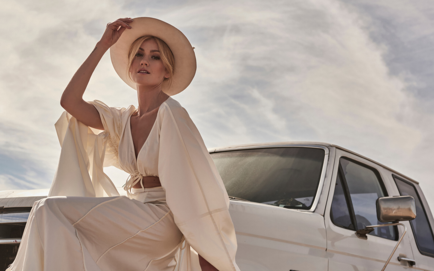 Актриса Кэтрин Макнамара в белом костюме сидит на автомобиле