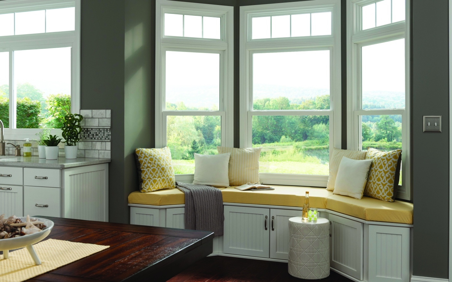 Уютная светлая кухня с эркером в загородном доме в зеленых тонах