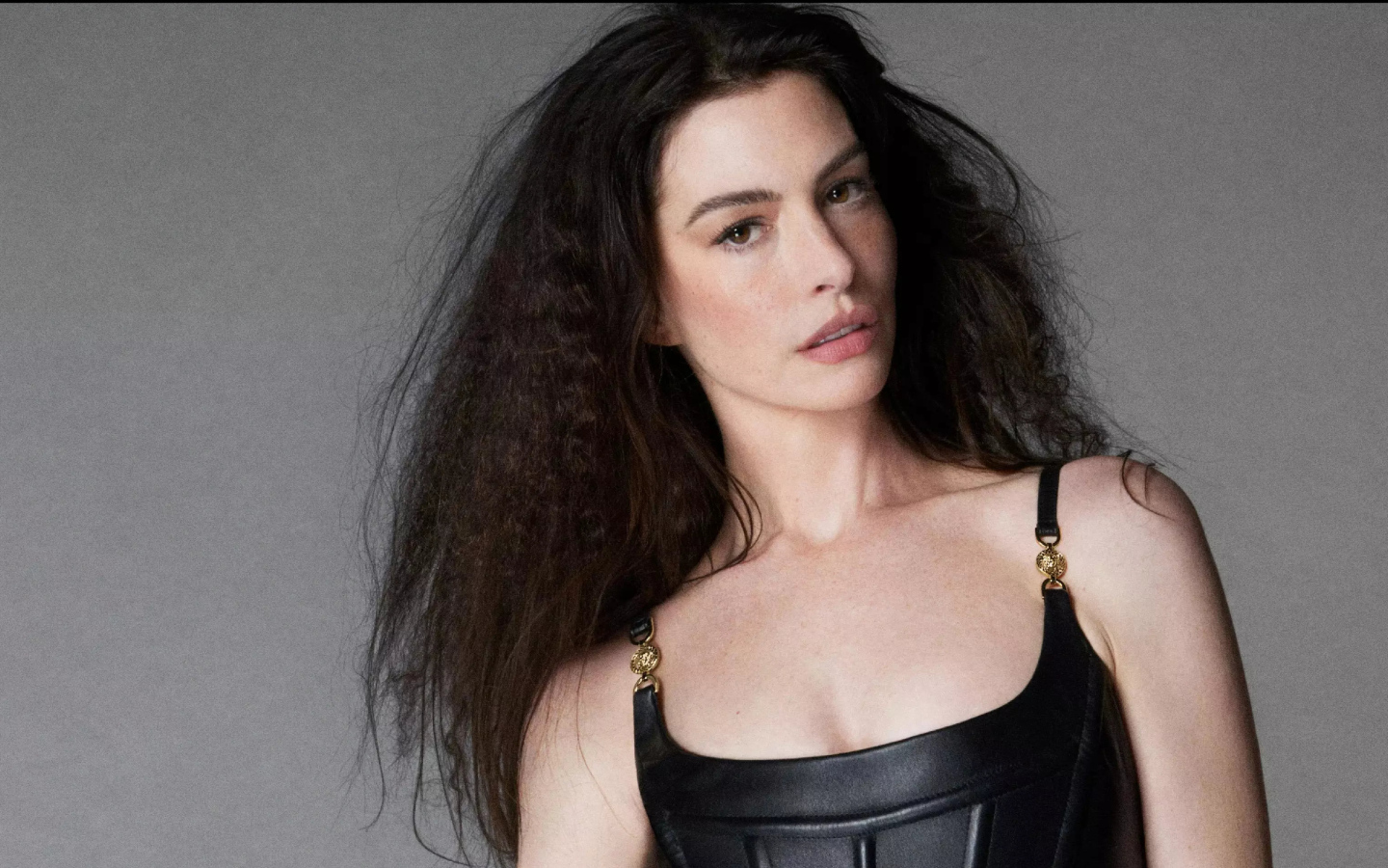 Длинноволосая актриса Энн Хэтэуэй на сером фоне