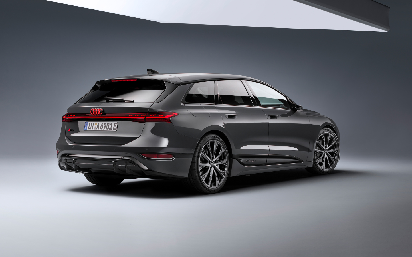 Автомобиль Audi A6 Avant e-tron S line 2024 года на сером фоне вид сзади