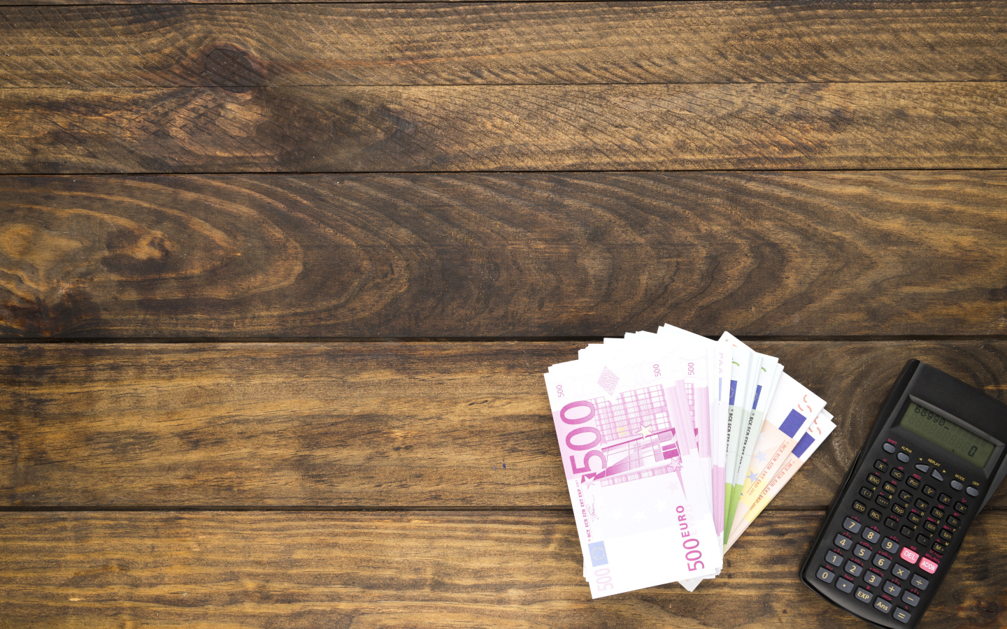 Купюры и калькулятор на деревянном фоне