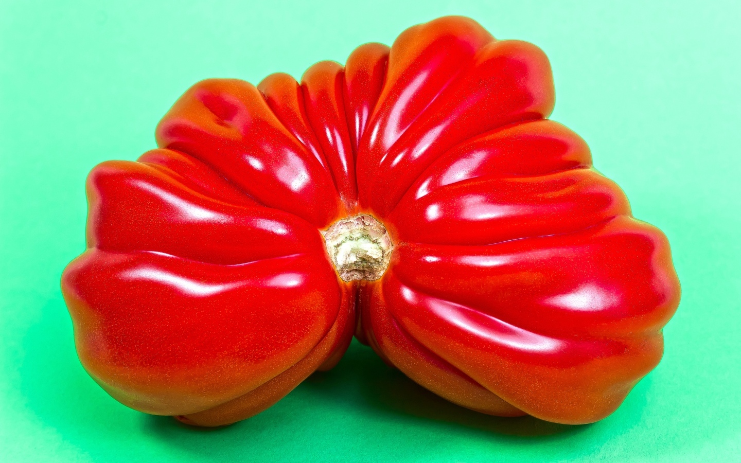 Большой спелый красный томат на зеленом фоне