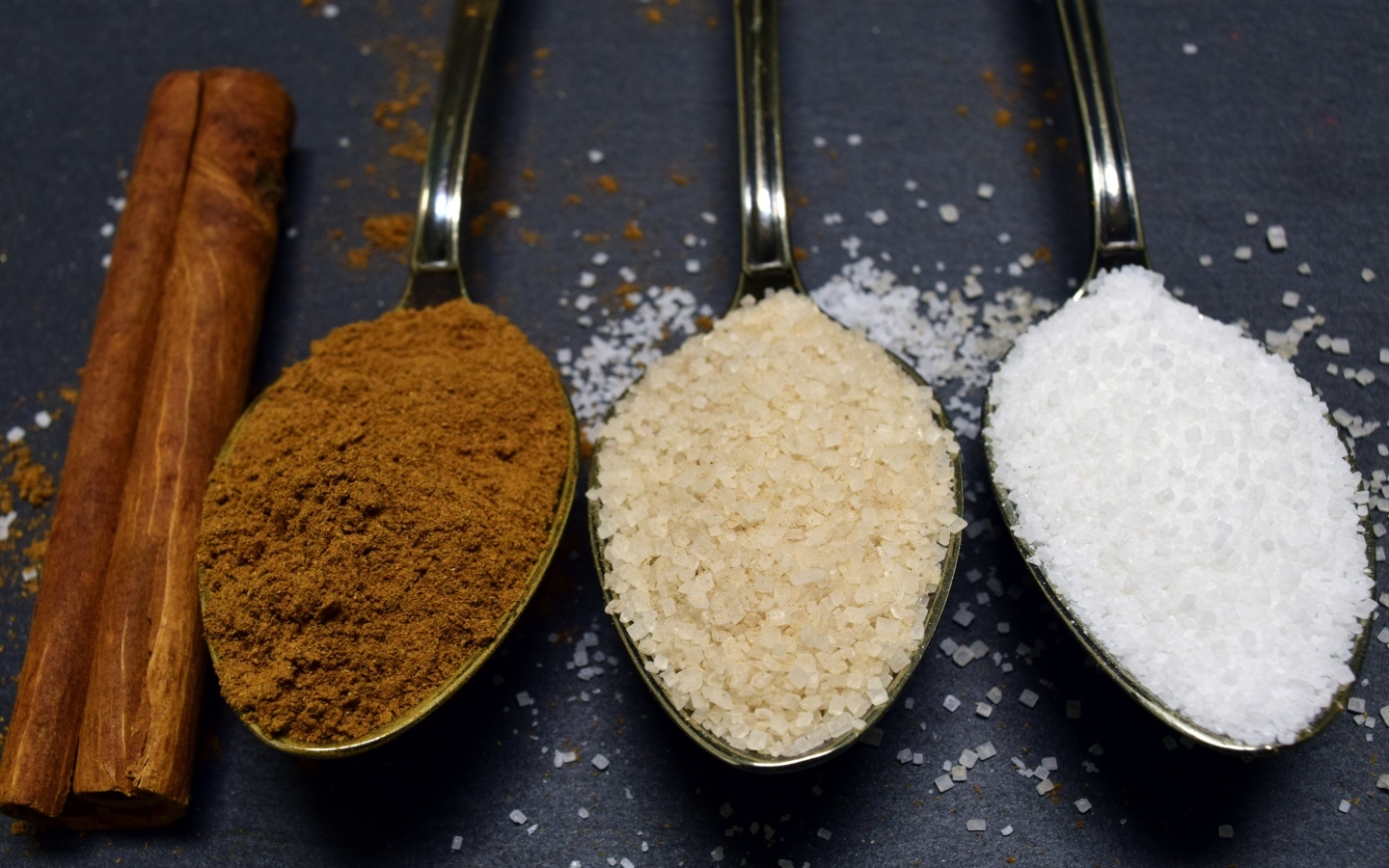 Три ложки со специями на сером столе