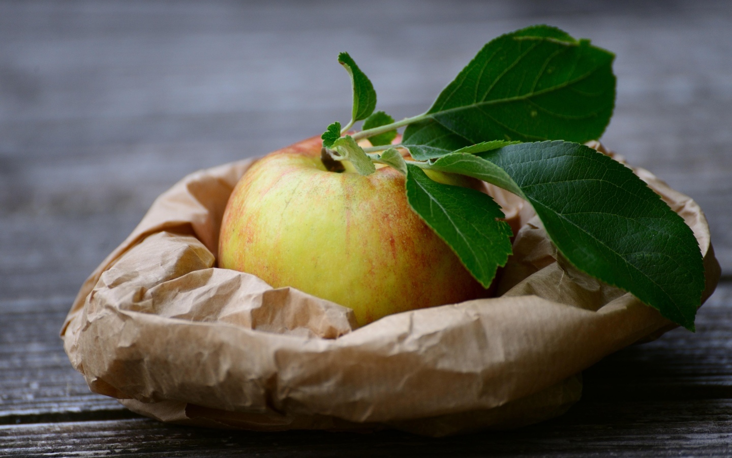 Яблоко с зелеными листьями на бумаге