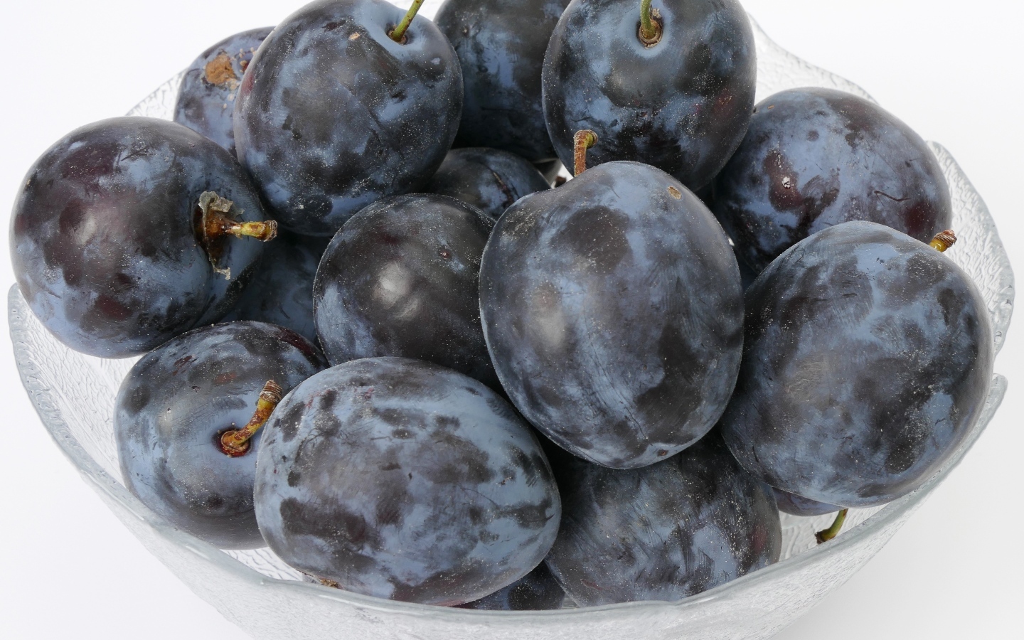 Стеклянная тарелка с вкусными синими сливами