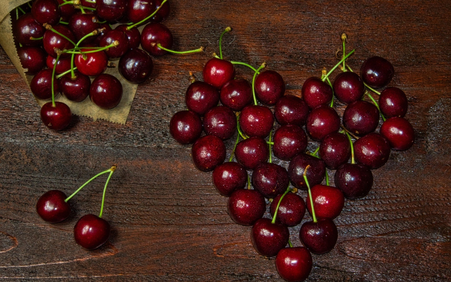 Сердце из спелых ягод черешни на деревянном столе