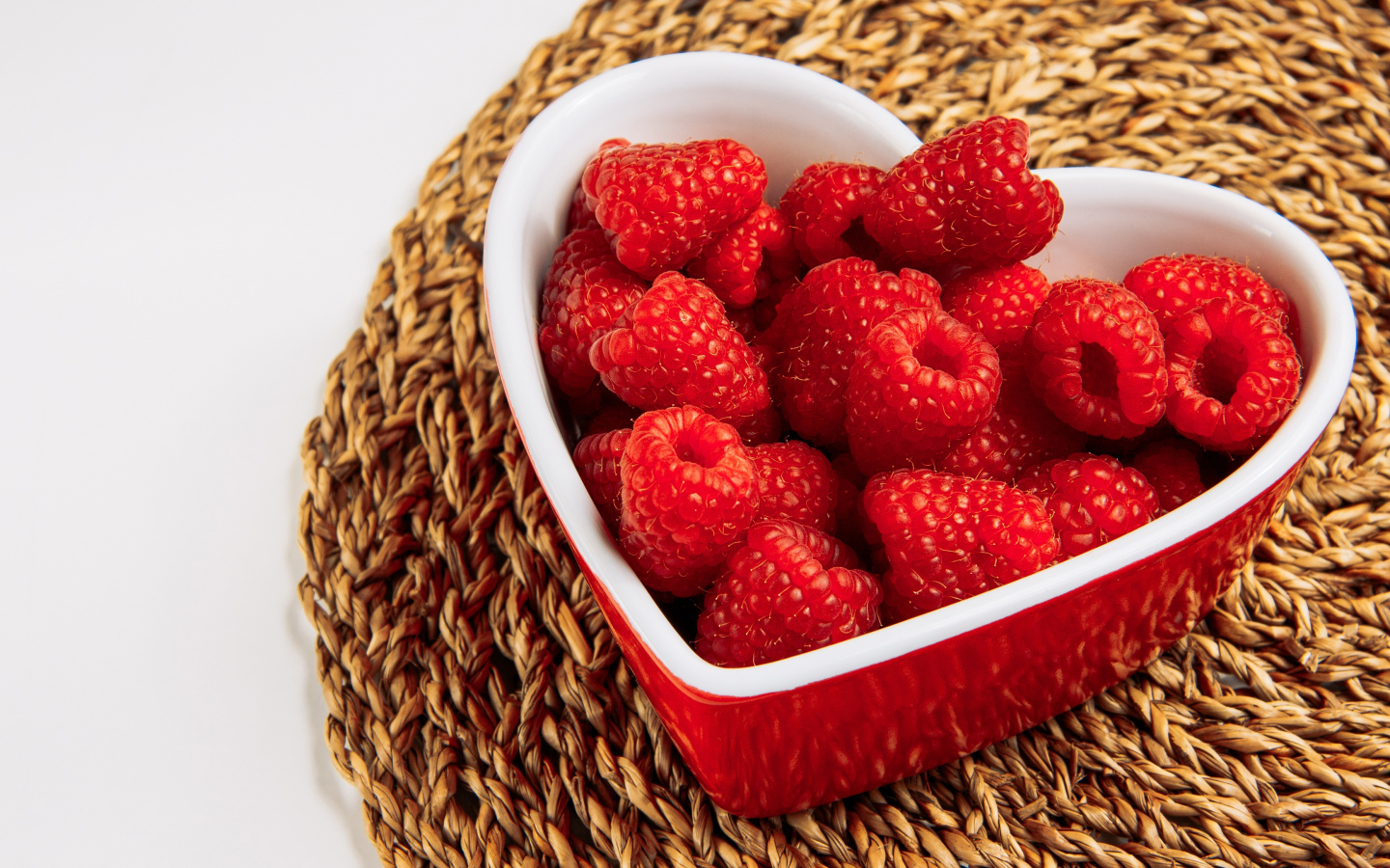 Малина в тарелке в виде сердца на столе