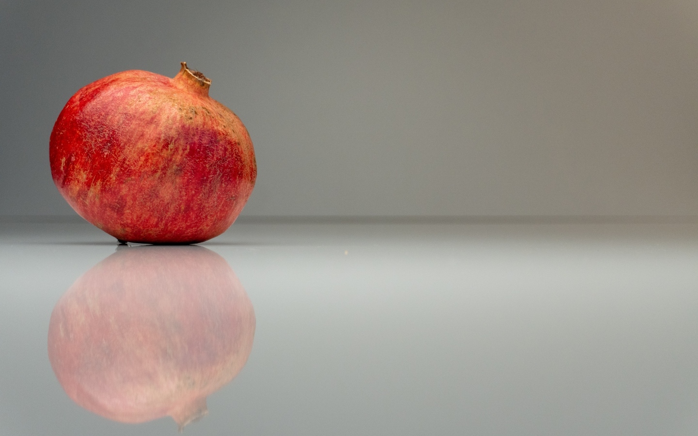 Красный гранат отражается в поверхности на сером фоне