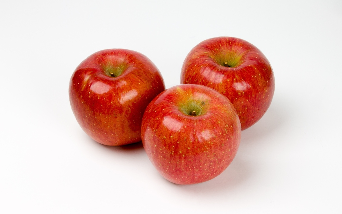 Три красных яблока на белом фоне