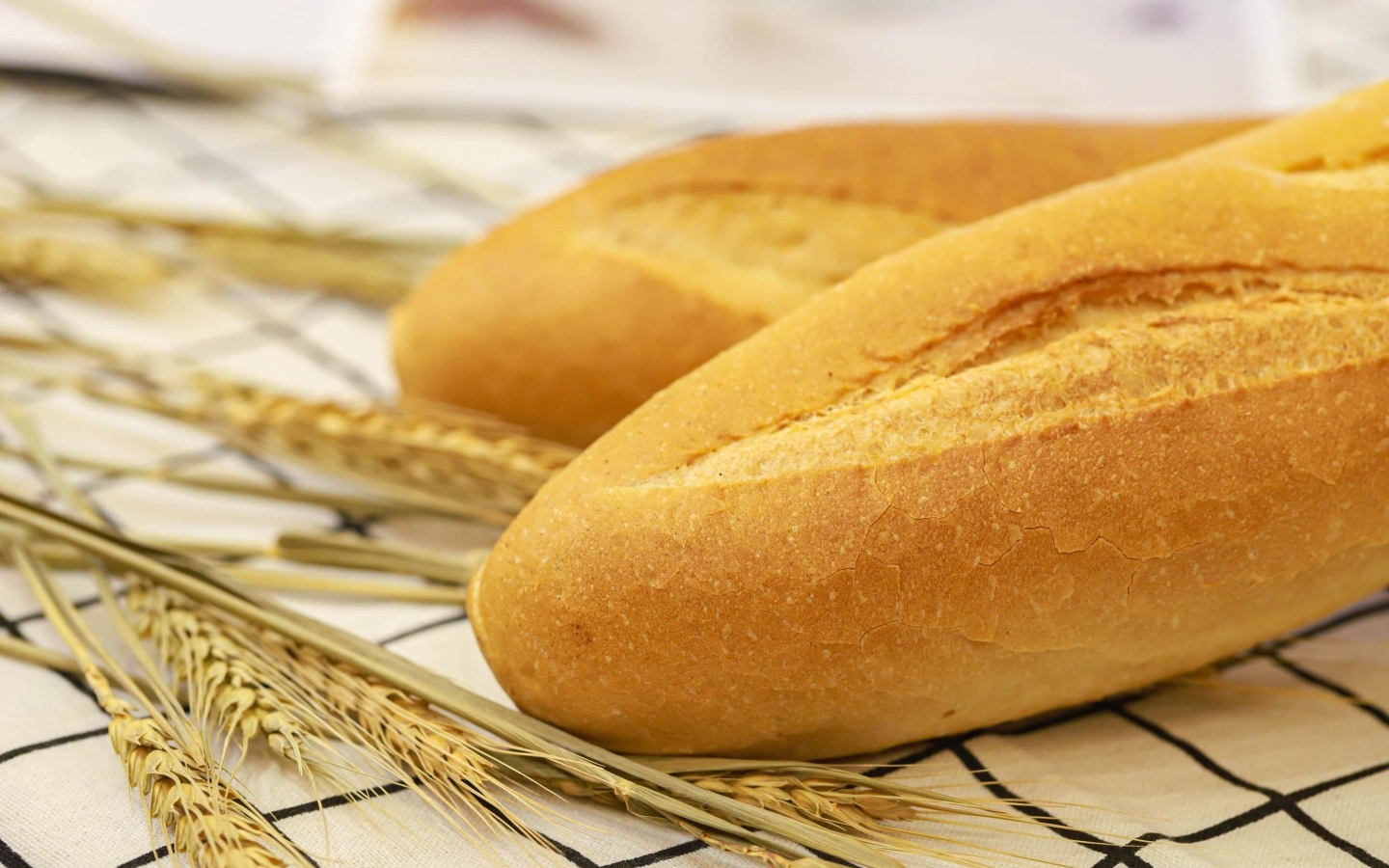 Два батона на столе с колосьями пшеницы