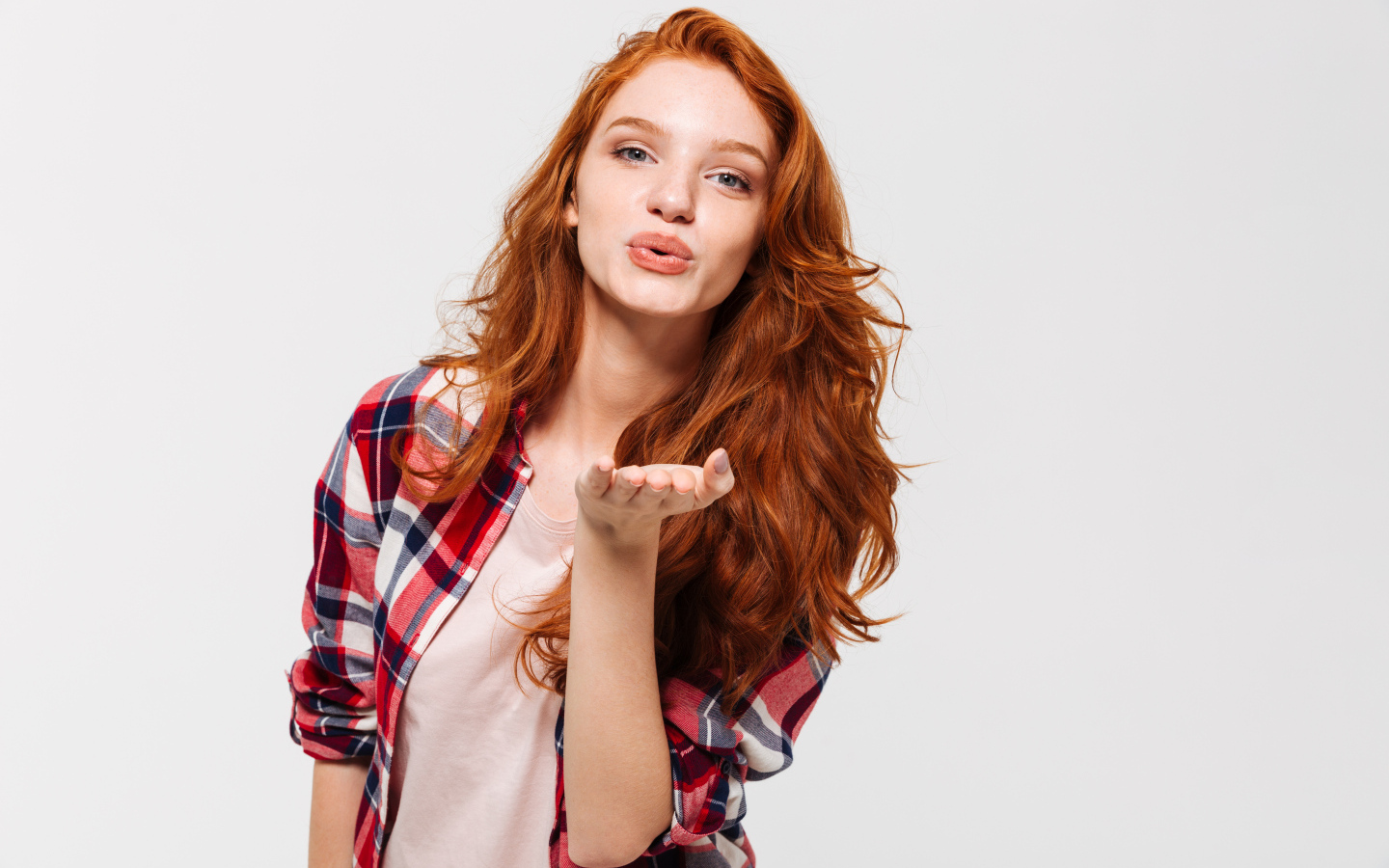 Красивая рыжеволосая девушка шлет воздушный поцелуй