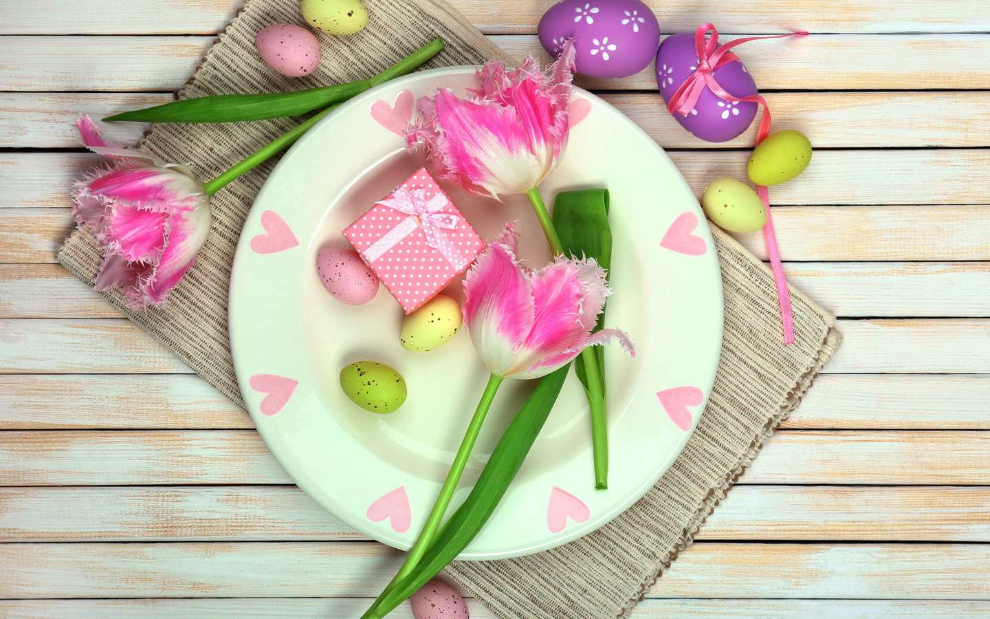 Пасхальные яйца с тюльпанами на тарелке на столе