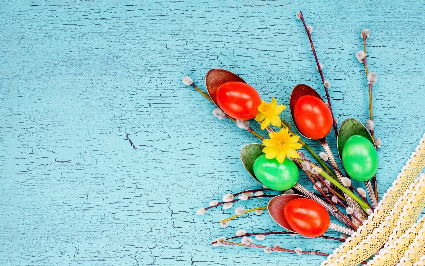 Ложки с разноцветными яйцами и ветками вербы на голубом фоне на Пасху