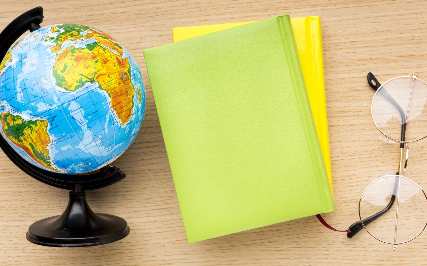 Глобус, тетради и очки на школьной парте