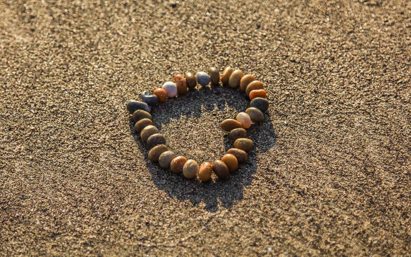 Сердце из камней на морском песке летом