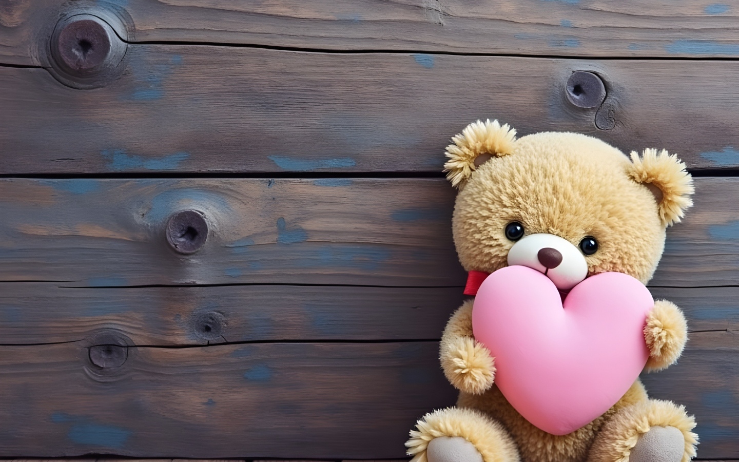 Маленький плюшевый мишка с розовым сердцем у стены