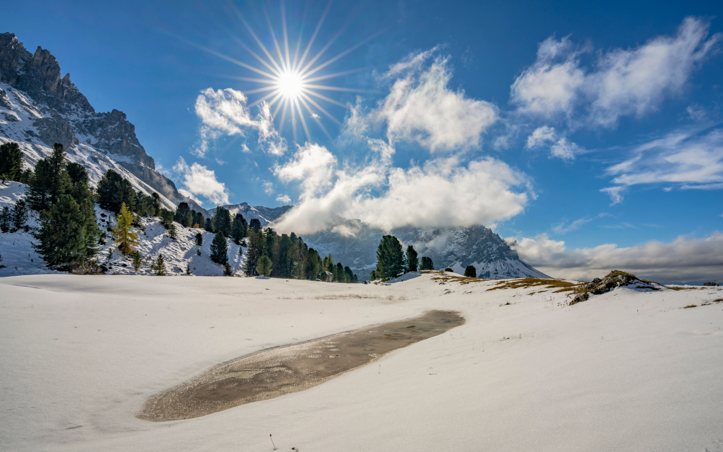 Яркое солнце над горами у заледеневшего озера