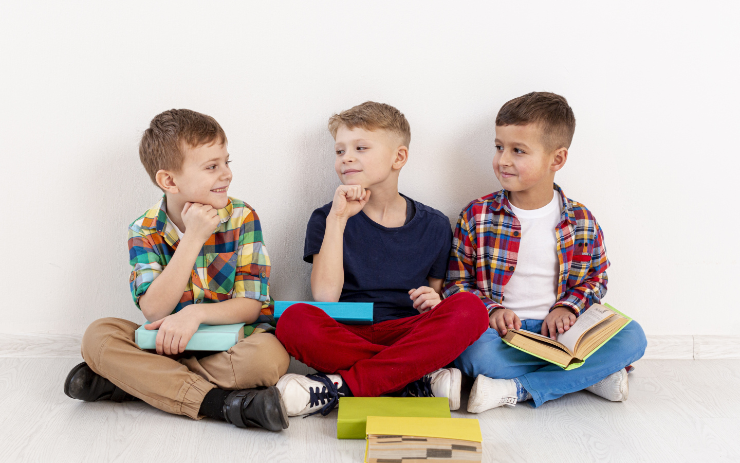 Три мальчика с книгами сидят у стены