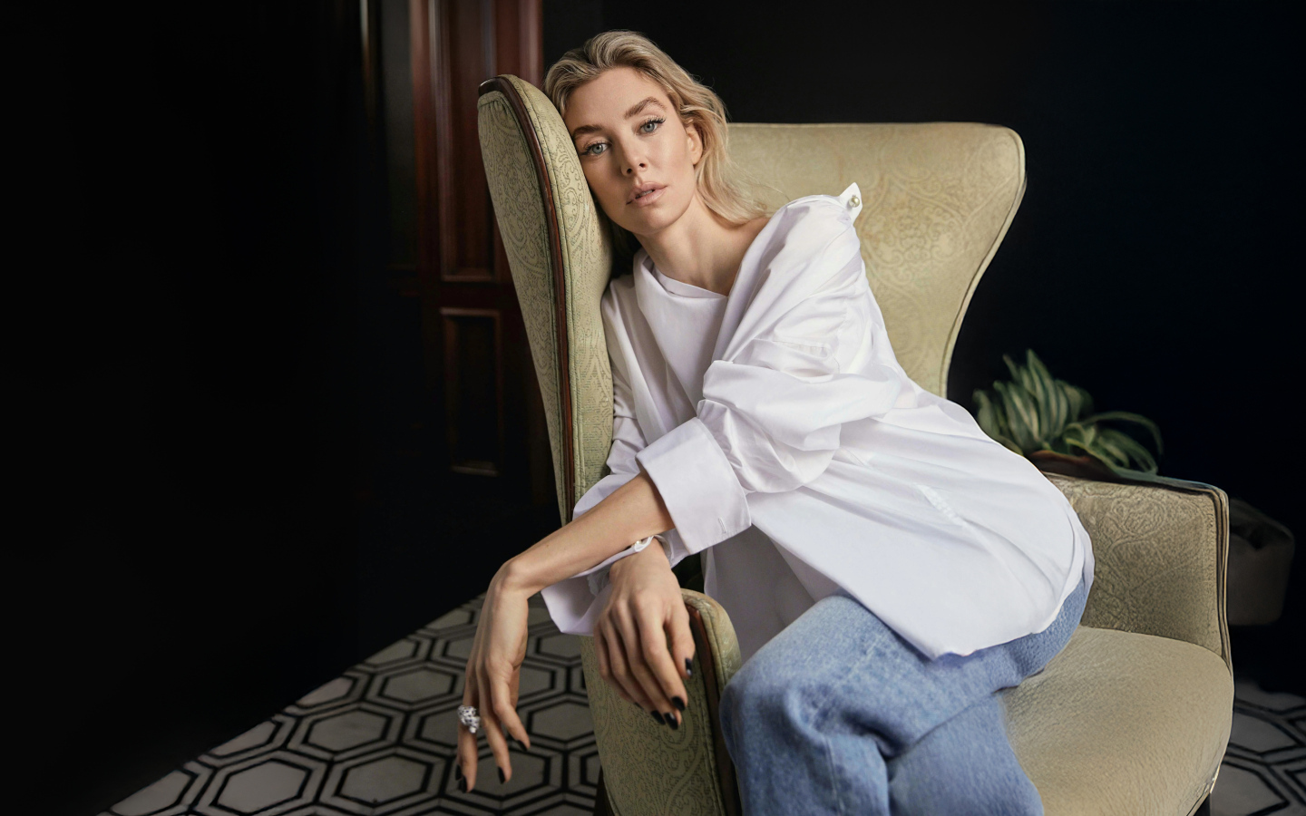 Актриса Ванесса Кирби в белой рубашке сидит на кресле
