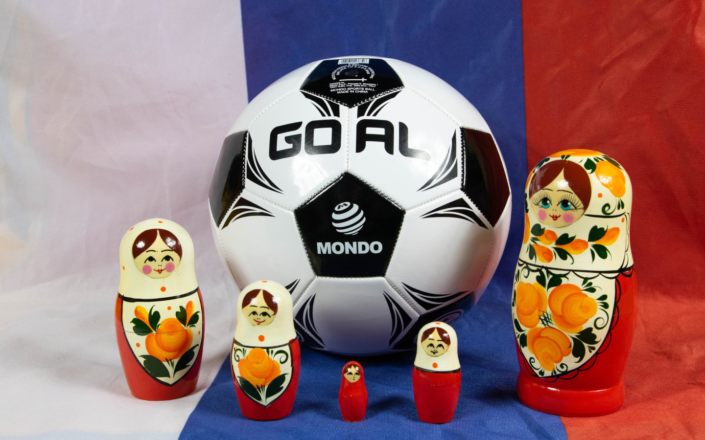Матрешки и футбольный мяч на фоне флага России