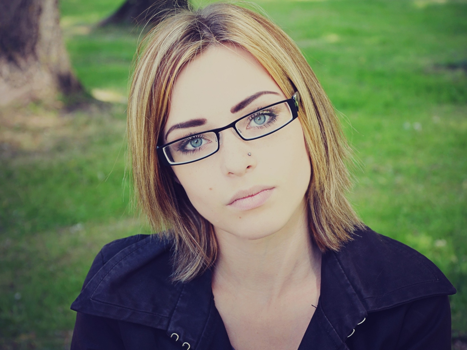 Blonde girl with piercings in the nose with glasses