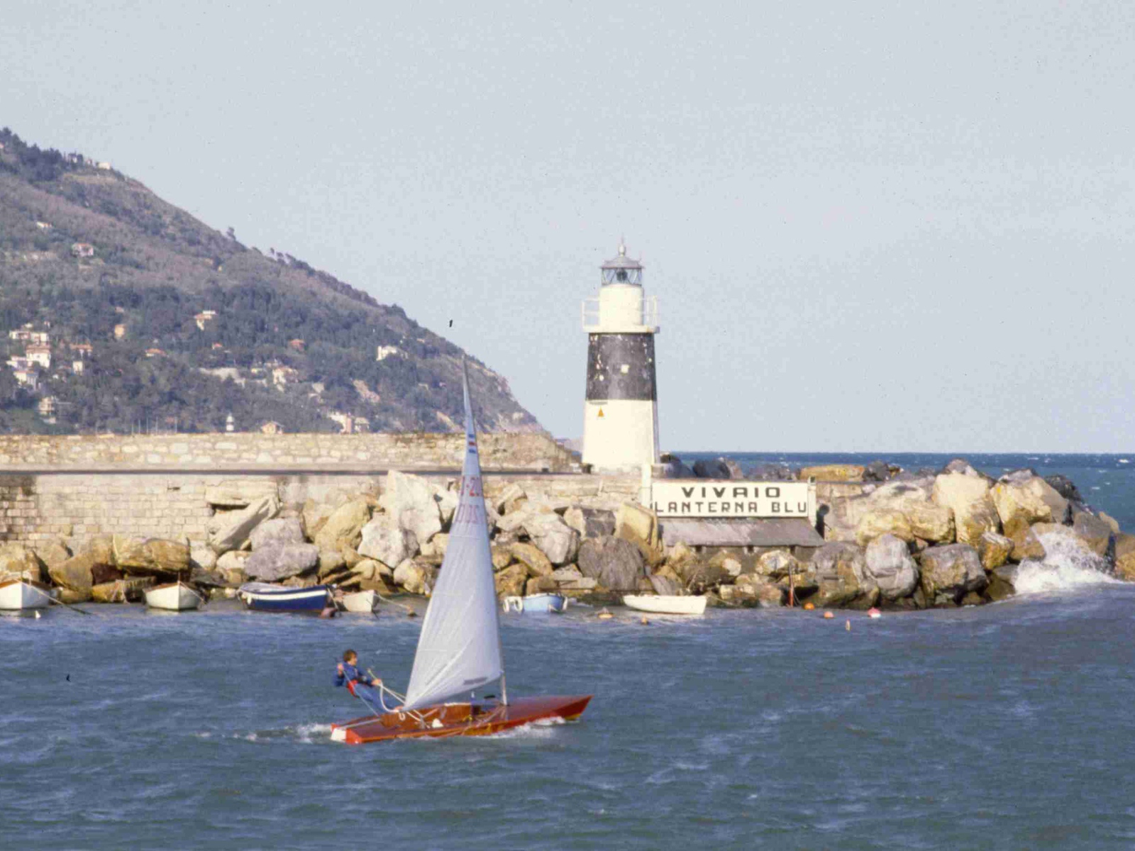 Лодка на фоне маяка на курорте Империя, Италия