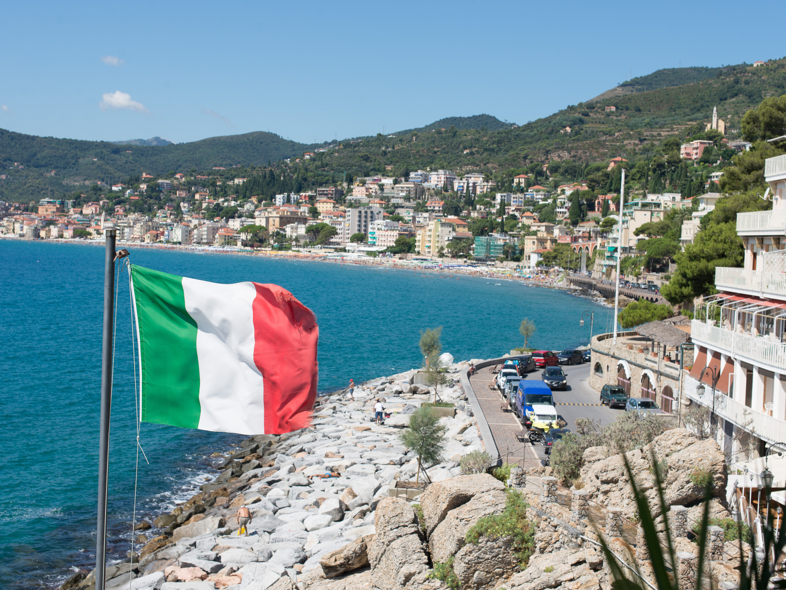 Флаг на фоне пляжа на курорте Алассио, Италия