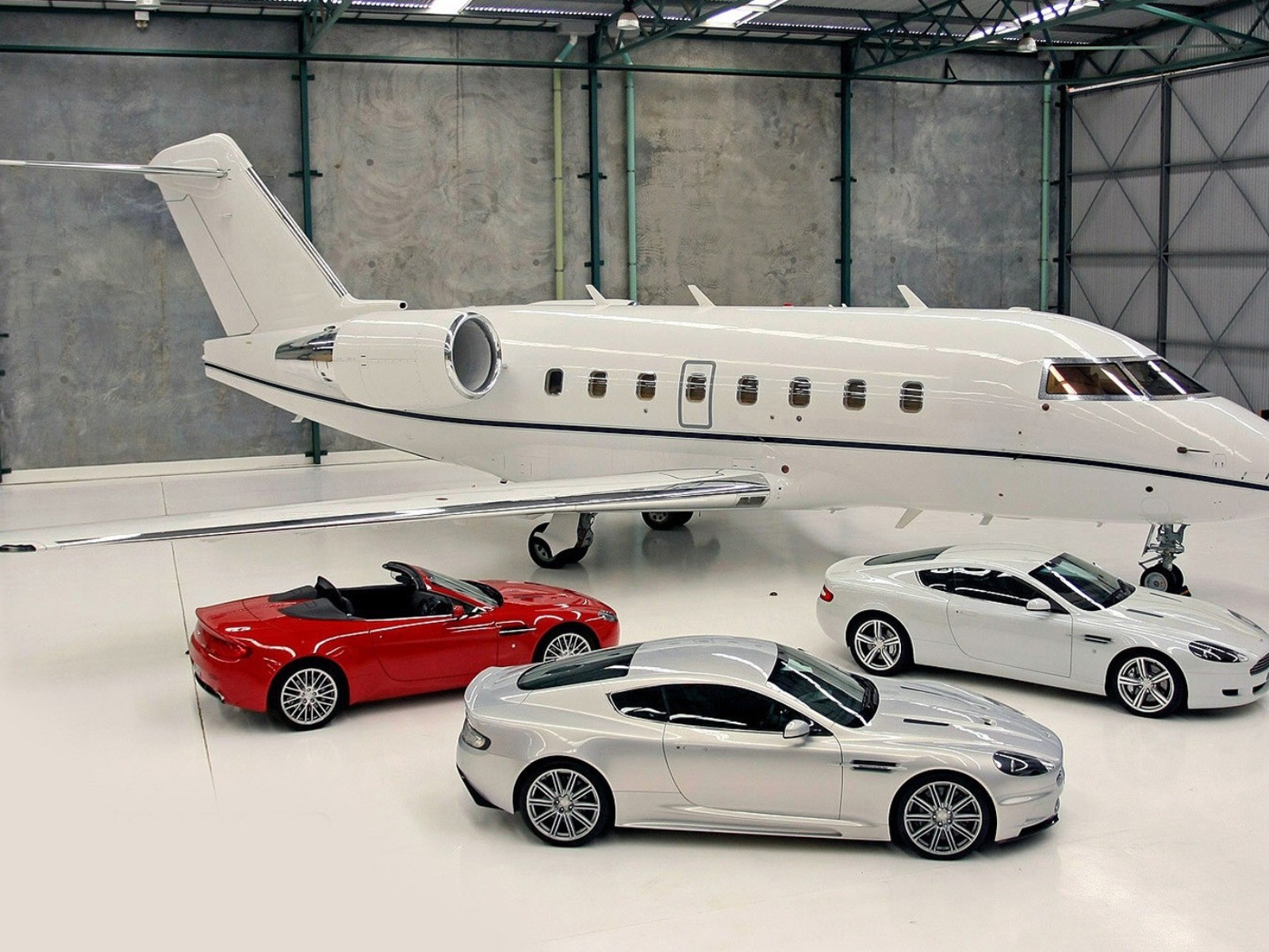 Автомобили Aston Martin в ангаре у частного самолета