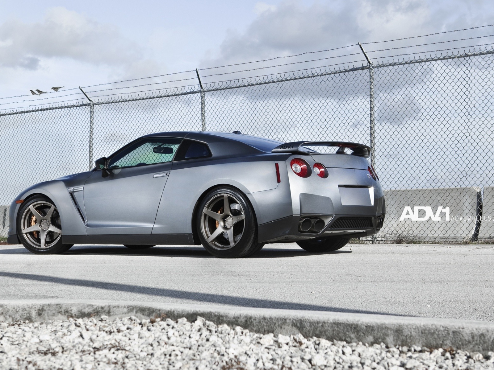 Серый Nissan Skyline GT-R R35 у забора из сетки