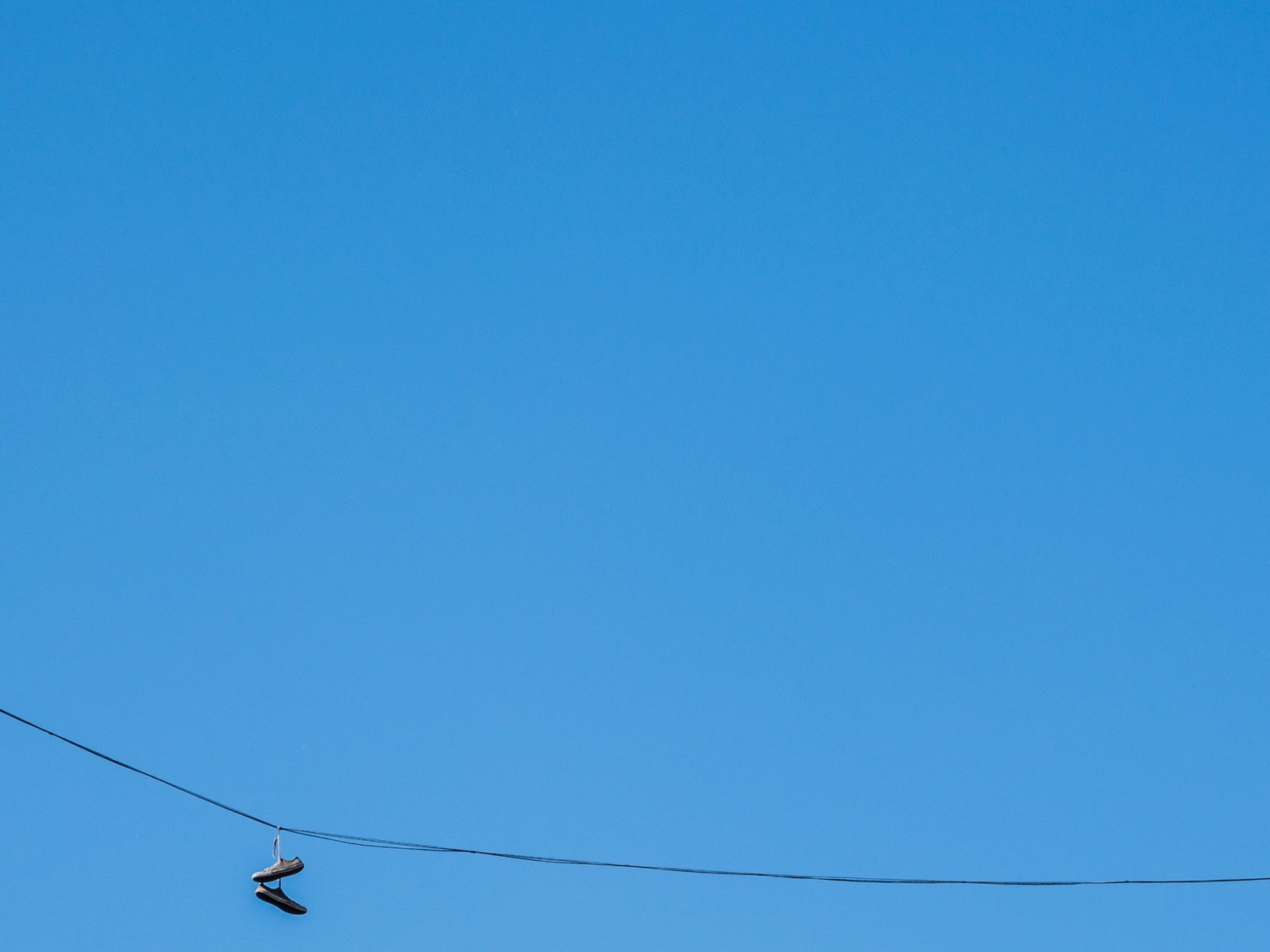 Кеды висят на проводе на фоне голубого неба