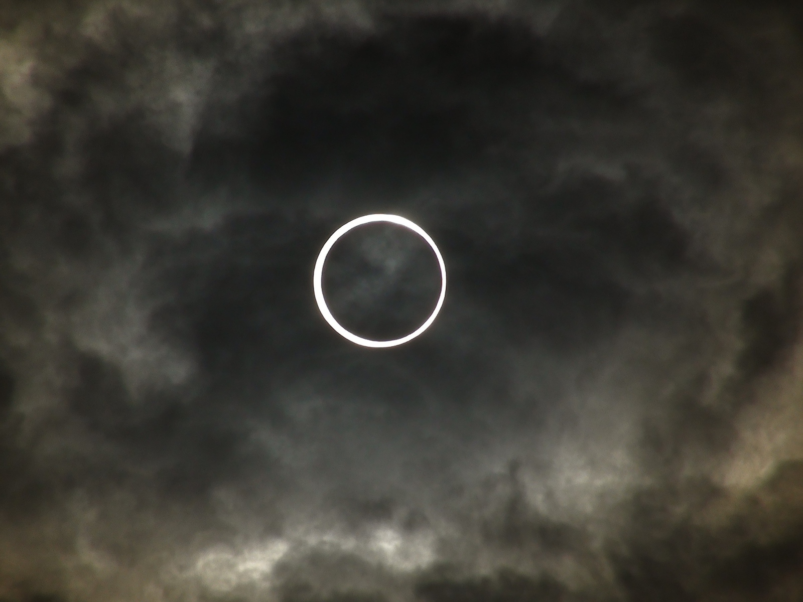 Белый круг на фоне темных облаков